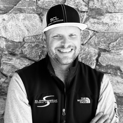 A white male in a baseball cap smiles at the camera